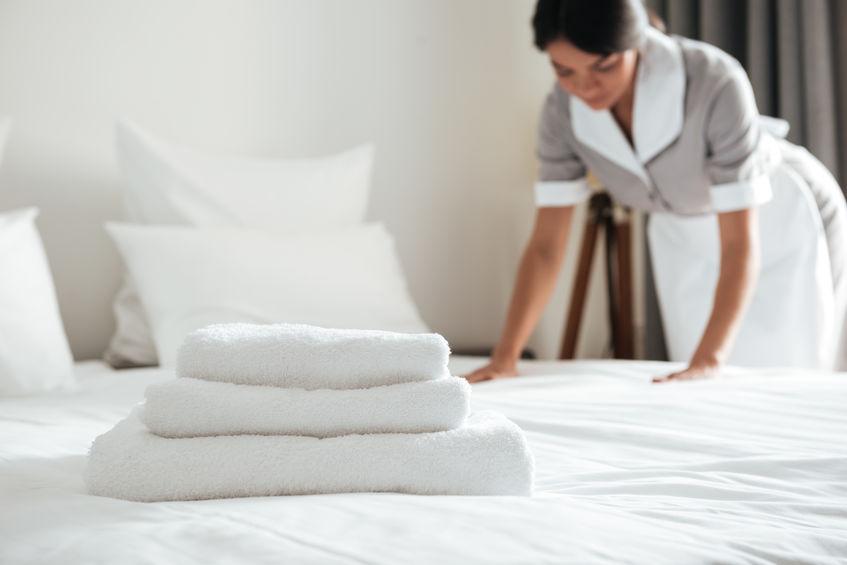 Housekeeper making bed with towels on it